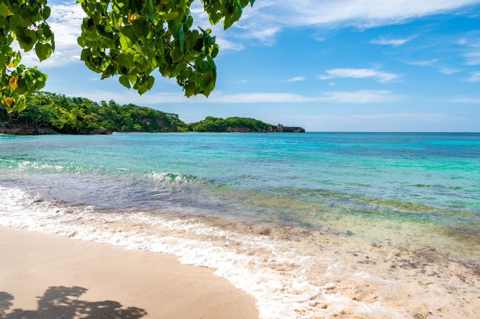 Clear blue skies on sunny summer day with turquoise ocean water on white sand beach